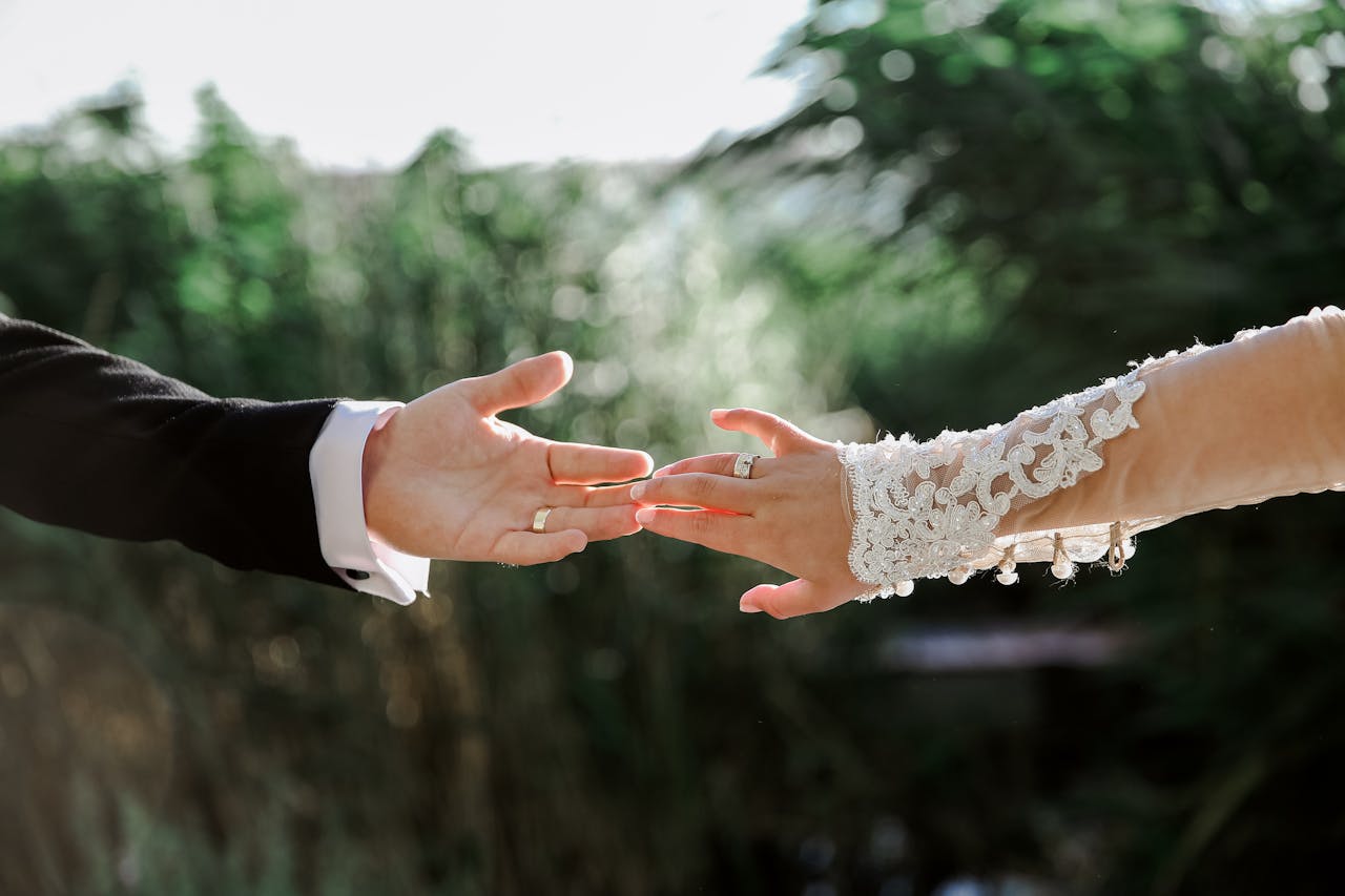 gallery-2 A couple gently reaching for each other's hands during their outdoor wedding ceremony.